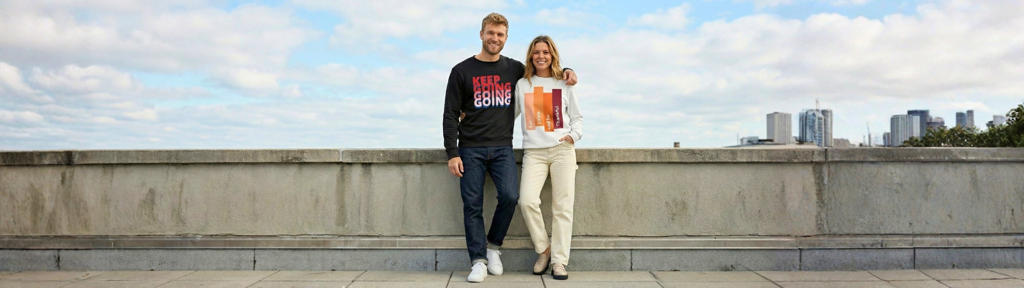 Two people standing on a bridge with a city skyline in the background